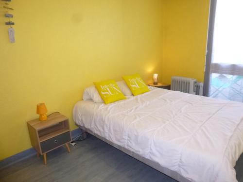 - une chambre avec des murs jaunes et un lit avec des oreillers jaunes dans l'établissement Appartement familial avec balcon, à 50m de la plage – 2 pièces, 4 couchages, WiFi et parking gratuits - FR-1-224C-153, à Saint-Hilaire-de-Riez