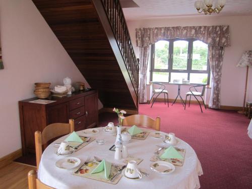 een eetkamer met een tafel met een witte tafeldoek bij Greenfields Farmhouse in Ballylongford