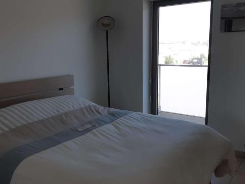 Cette chambre comprend un lit blanc et une grande fenêtre. dans l'établissement Appart 2 ch. avec accès plage et parking privé - FR-1-674-34, à Berck-sur-Mer