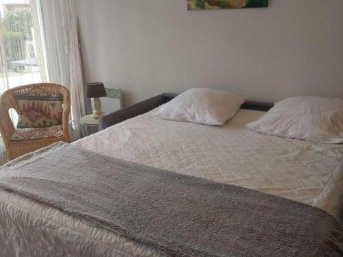 - un lit avec deux oreillers et une chaise dans une chambre dans l'établissement Appartement RDC avec Terrasse, Jardin et Accès Plage - Capacité 4 Pers, Animaux et Fumeurs Non Admis - FR-1-674-4, à Berck-sur-Mer