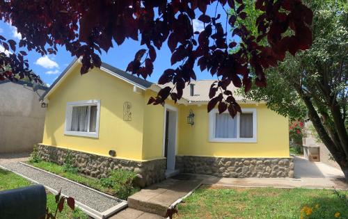 a yellow house with a tree in front of it at Las Rucas in San Martín de los Andes