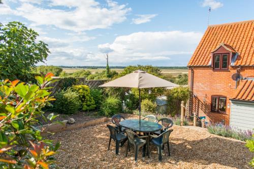 a table and chairs with an umbrella in a garden at Host & Stay - Laylands Yard in Wells next the Sea
