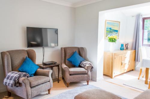 a living room with two chairs and a flat screen tv at Host & Stay - Laylands Yard in Wells next the Sea
