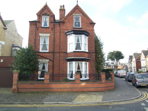 a red brick house with a fence in front of it at The Hollies in Bridlington
