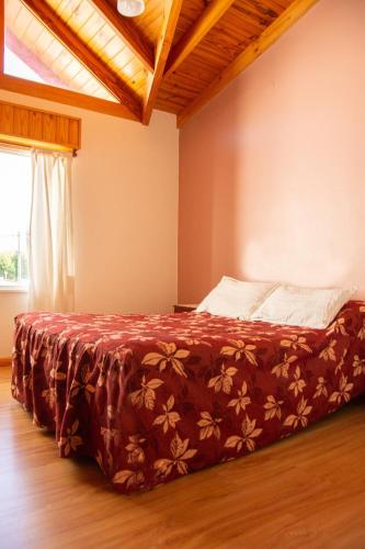 una camera da letto con un letto con una coperta rossa di Apartment Lourdes a El Calafate