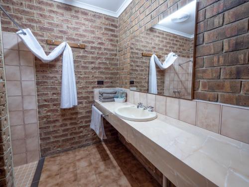 a bathroom with a sink and a brick wall at Eildon Parkview Motor Inn Room 9 in Eildon