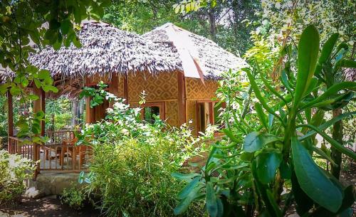 a small wooden house with a thatch roof at Sunset Cottages in Hitokalak