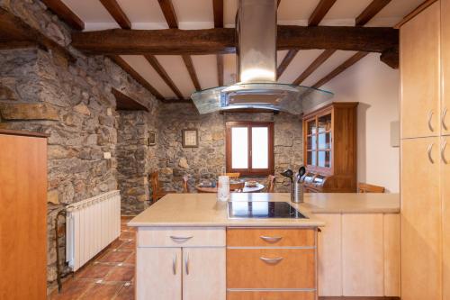 a kitchen with wooden cabinets and a stone wall at Erribera - baskeyrentals in Berriatúa