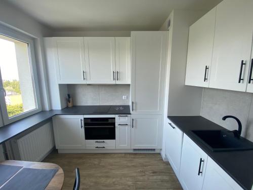 cocina con armarios blancos, fregadero y mesa en Brand New Top Floor Apartment at Mokotow en Varsovia