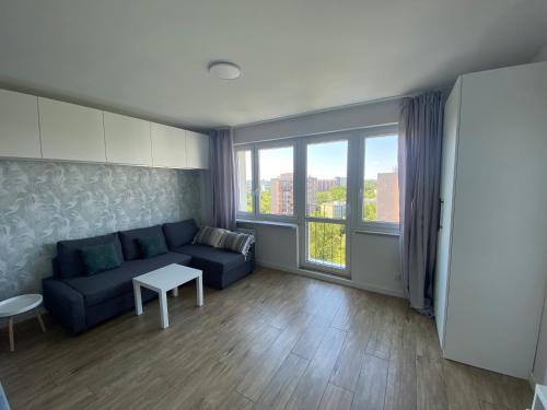 sala de estar con sofá y ventana grande en Brand New Top Floor Apartment at Mokotow en Varsovia