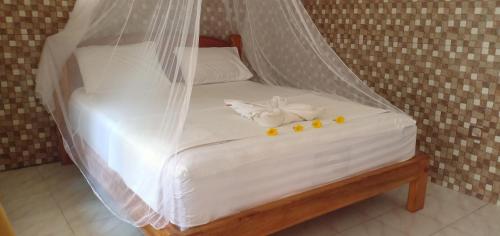 Una cama con sábanas blancas y flores amarillas. en Pondok Pandi, en Gili Trawangan
