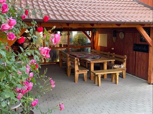 un patio con mesa, bancos y rosas en Gáll vendégház en Lăzarea