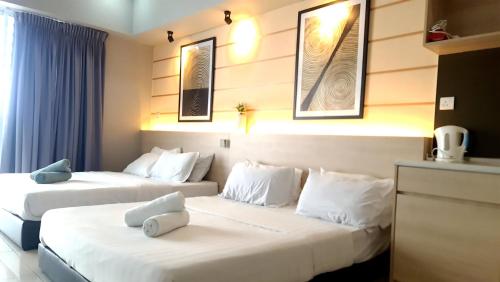 two beds in a hotel room with white pillows at Aeropod 2 Queen Bed Near Airport & KK city Free Parking Netflix in Kota Kinabalu