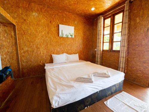 a bedroom with a bed with white sheets and a window at Bottle Beach 2 Bungalows in Bottle Beach