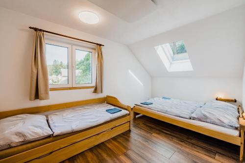 duas camas num quarto com duas janelas em Na Želivce chalupa Gabriela em Želiv