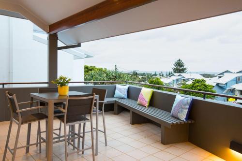 uma varanda com um banco, uma mesa e cadeiras em Coffs Jetty Beach House em Coffs Harbour