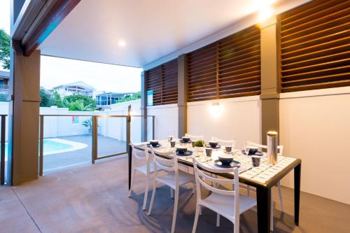 ein Esszimmer mit einem Tisch und weißen Stühlen in der Unterkunft Coffs Jetty Beach House in Coffs Harbour