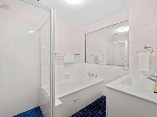 Baño blanco con bañera y lavamanos en Hawaiian Gardens Unit 22 en Coffs Harbour