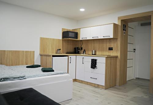 a small kitchen with white cabinets and a bed at Apartamenty Pawełek in Zator