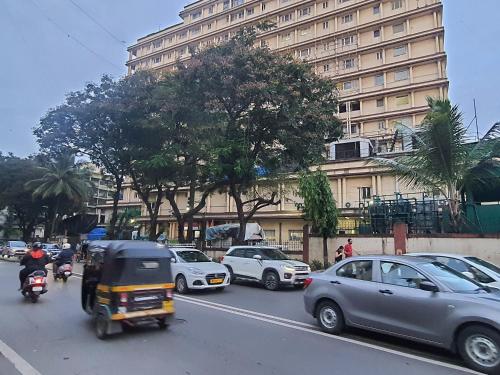 a busy city street with cars and motorcycles and a tall building at OSI Apartments Lilavati Bandra in Mumbai