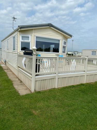 una pequeña casa en una valla con porche en L&g FAMILY HOLIDAYS MILLFIELDS 6 BERTH FAMILYS ONLY AND THE LEAD PERSON MUST BE OVER 30s, en Ingoldmells