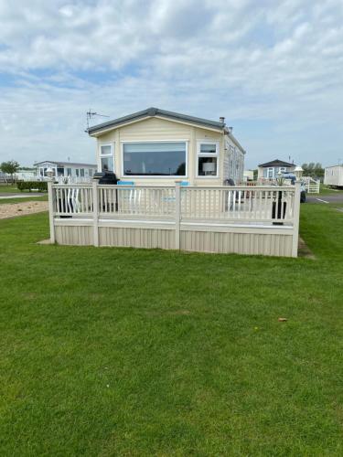 a small house with a white fence on the grass at L&g FAMILY HOLIDAYS MILLFIELDS 6 BERTH FAMILYS ONLY AND THE LEAD PERSON MUST BE OVER 30s in Ingoldmells