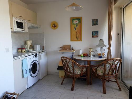 une cuisine avec une table et des chaises ainsi qu'un lave-linge dans l'établissement PORT FREJUS Studio Cabine 100m des plages 4 Person, à Fréjus
