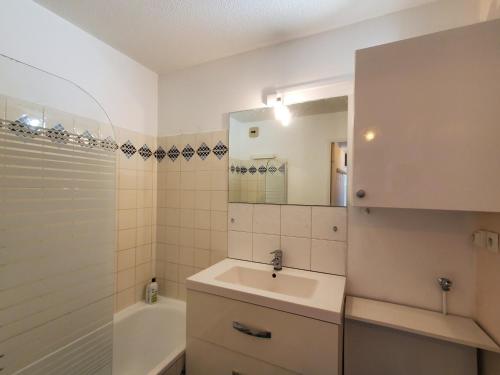 une salle de bain avec un lavabo, un miroir et une baignoire dans l'établissement MIOUGRANO 2 Pieces Climatise 47m2 Piscine, Parking, à Fréjus