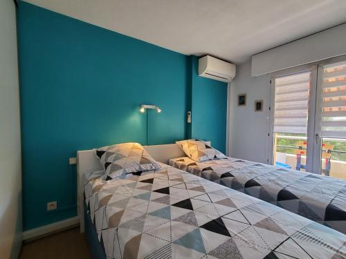une chambre avec deux lits et un mur bleu dans l'établissement MIOUGRANO 2 Pieces Climatise 47m2 Piscine, Parking, à Fréjus