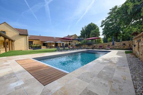 a swimming pool with a wooden deck next to a house at Domaine du Bugassou, Chambres, Table d'hôtes & SPA in Belvès