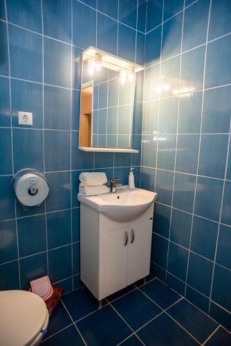 a blue tiled bathroom with a sink and a toilet at HOTEL MARION POIANA in Dumbrăveni