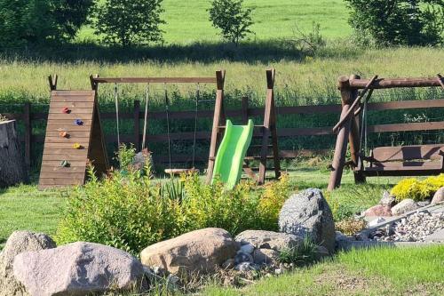 a garden with a playground and a swing set at Domek z Sauną i balią jakuzii w głuszy in Borzynowo