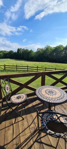 two tables and chairs sitting next to a fence at Domek z Sauną i balią jakuzii w głuszy in Borzynowo