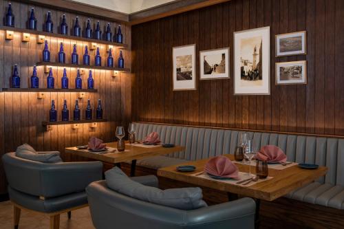 a restaurant with two tables and blue bottles on the wall at Alwadi Hotel Doha - MGallery Collection in Doha
