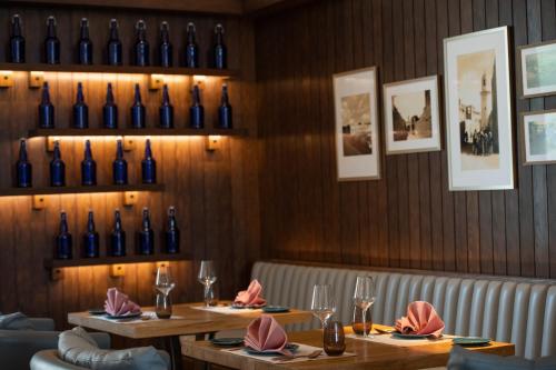 a restaurant with two tables with wine bottles on the wall at Alwadi Hotel Doha - MGallery Collection in Doha