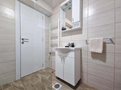 ein weißes Badezimmer mit Waschbecken und Spiegel in der Unterkunft Apartmani Gala Žabljak in Žabljak