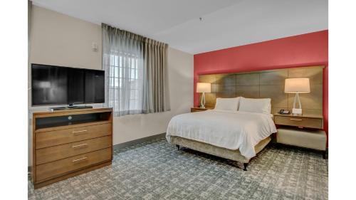 a bedroom with a large bed and a flat screen tv at Staybridge Suites Salt Lake-West Valley City by IHG in West Valley City