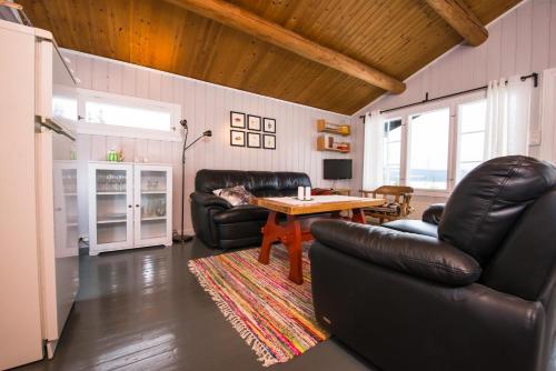 uma sala de estar com duas cadeiras de couro e uma mesa em Nærglimt - cabin by the lake Næra em Ringsaker