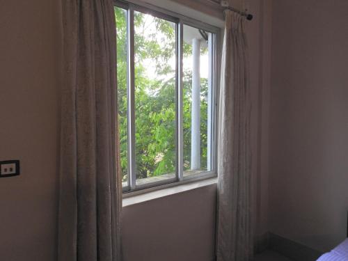 a window with a curtain in a room at Lake Side Resort Neermahal in Melāghar
