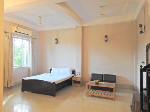a bedroom with a bed and a table and a window at Lake Side Resort Neermahal in Melāghar
