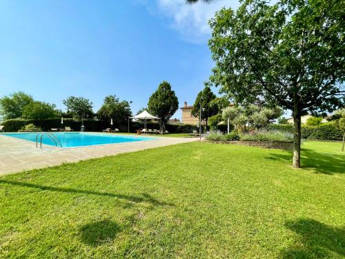 un gran patio con piscina y un árbol en Agriturismo La Colmata, en Cesa