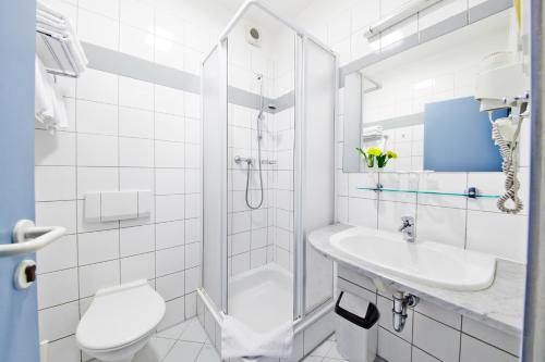 a white bathroom with a shower and a toilet and a sink at Hotel Tulipan Pruhonice in Pruhonice