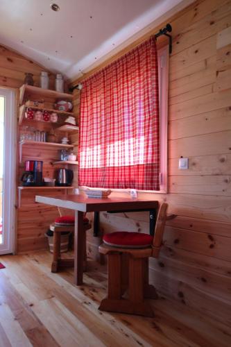 Cette chambre en bois dispose d'une table et d'une fenêtre. dans l'établissement roulotte impériale perchée-, à Sembadel