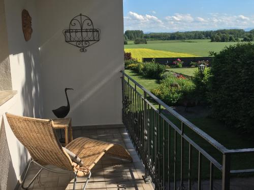 a woman sitting in a chair on a porch with a view of a field at Gemütliche und geräumige Unterkunft, Nähe Linz in Luftenberg an der Donau