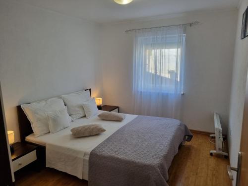 1 dormitorio con 1 cama con sábanas blancas y ventana en Apartment Boba, en Sinj