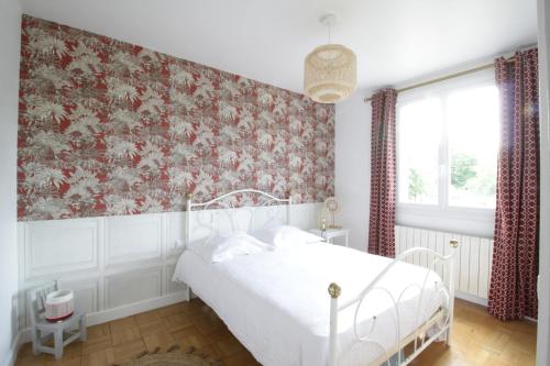 a bedroom with a white bed and a floral wallpaper at L'hermoyse Cosy centre ville in La Selle-en-Hermoy