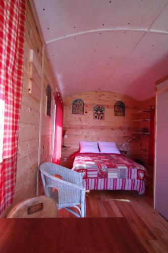 une chambre avec un lit dans une cabane en rondins dans l'établissement roulotte impériale perchée-, à Sembadel
