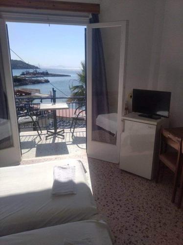 a bedroom with a balcony with a view of the ocean at Ammoudia Rooms in Agia Marina Aegina