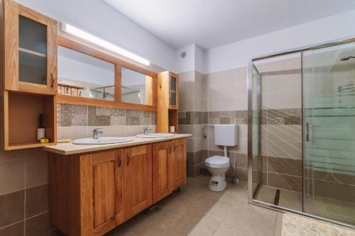 La salle de bains est pourvue de 2 lavabos et d'une douche. dans l'établissement Pensiunea Bradet, à Malaia