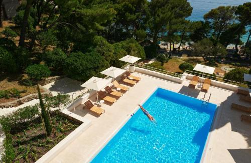 uma vista sobre uma piscina com espreguiçadeiras e uma piscina em Bluesun Hotel Maestral em Brela